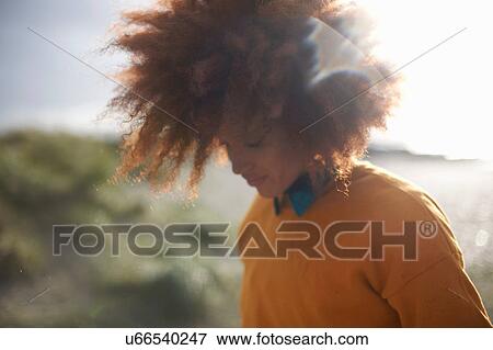 Stock Photo - Woman with afro hair on grassy dune. Fotosearch