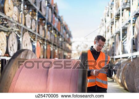 Worker inspecting cable reels with digital pad at cable storage facility View Large Photo Image Stock Photography - Worker inspecting cable reels with digital pad at cable storage facility. Fotosearch