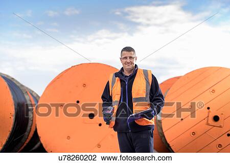 Worker inspecting electrical cable reels at cable storage facility, portrait View Large Photo Image Stock Image - Worker inspecting electrical cable reels at cable storage facility, portrait. Fotosearch