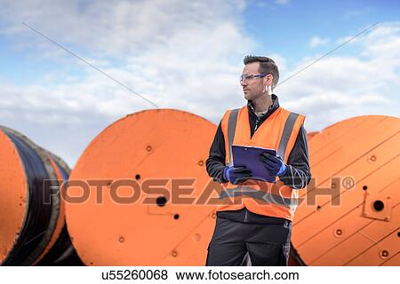 Worker inspecting electrical cable reels at cable storage facility, portrait View Large Photo Image Stock Photo - Worker inspecting electrical cable reels at cable storage facility, portrait. Fotosearch