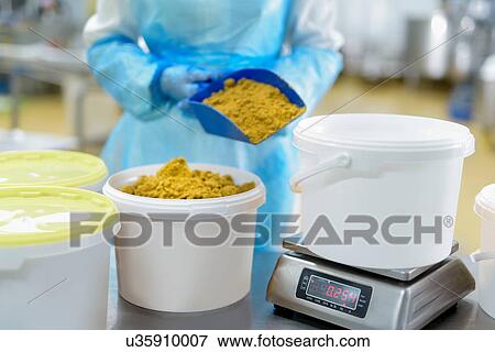 Stock Photo - Worker weighing curry powder in Asian food factory. Fotosearch