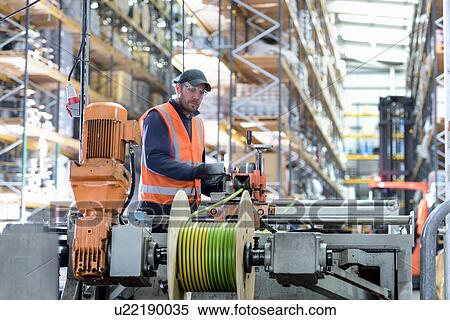 Stock Photography - Worker winding electrical cables at cable storage facility. Fotosearch