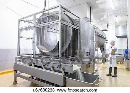 Stock Image - Worker with rice cooking machine in Asian food factory. Fotosearch