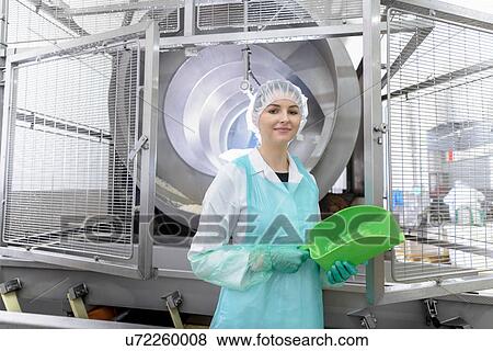 Stock Photo - Worker with rice cooking machine in Asian food factory. Fotosearch
