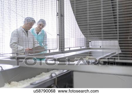 Stock Photo - Workers in discussion in Asian food factory. Fotosearch