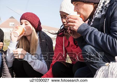 Young adult friends crouching on beach drinking takeaway coffee, Western Cape, South Africa View Large Photo Image Stock Photo - Young adult friends crouching on beach drinking takeaway coffee, Western Cape, South Africa. Fotosearch