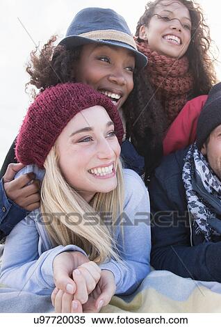Stock Photography - Young adult friends lying on top of each other at beach, Western Cape, South Africa. Fotosearch