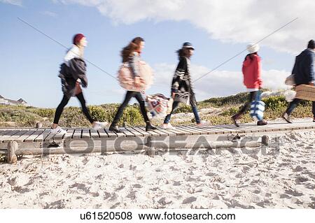 Stock Photo - Young adult friends on the move on beach boardwalk, Western Cape, South Africa. Fotosearch