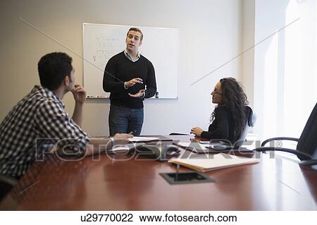 Stock Image - Young business people having meeting in board room. Fotosearch