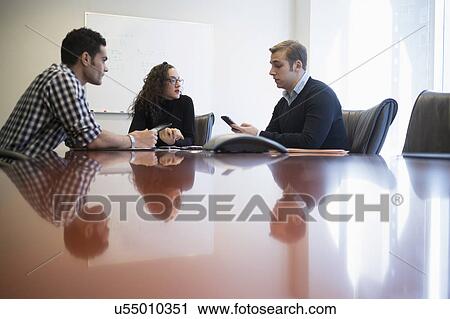 Stock Image - Young business people having meeting in board room. Fotosearch