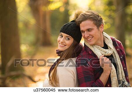 Young couple in forest, back to back, smiling View Large Photo Image Stock Photography - Young couple in forest, back to back, smiling. Fotosearch