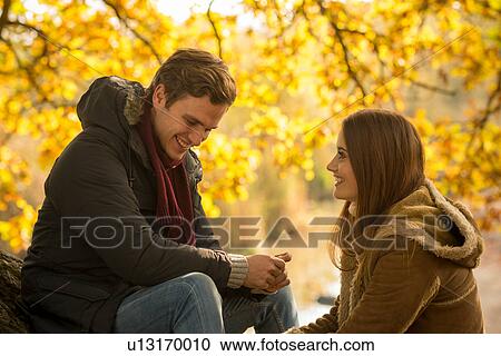 Young couple in forest, sitting face to face, smiling View Large Photo Image Stock Image - Young couple in forest, sitting face to face, smiling. Fotosearch