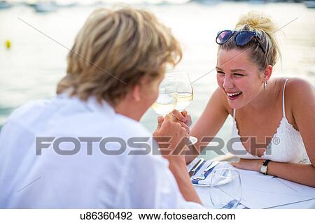 Young couple laughing at waterfront restaurant, Majorca, Spain View Large Photo Image Stock Image - Young couple laughing at waterfront restaurant, Majorca, Spain. Fotosearch