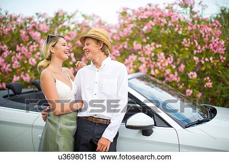 Stock Photo - Young couple leaning against convertible by blossoms, Majorca, Spain. Fotosearch