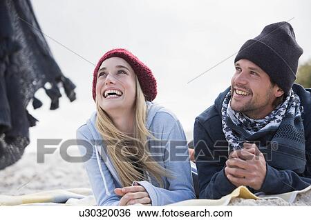Young couple looking up from picnic blanket at beach, Western Cape, South Africa View Large Photo Image Stock Photograph - Young couple looking up from picnic blanket at beach, Western Cape, South Africa. Fotosearch