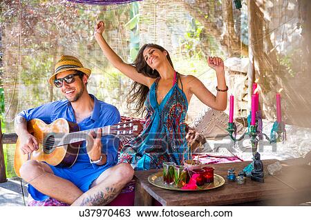 Stock Image - Young couple playing guitar smiling, dancing. Fotosearch