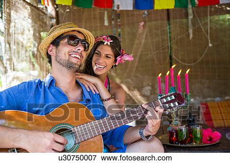 Stock Photo - Young couple playing guitar smiling. Fotosearch
