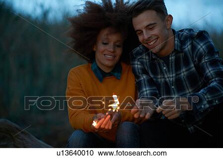 Young couple playing with sparklers in dunes at dusk View Large Photo Image Stock Image - Young couple playing with sparklers in dunes at dusk. Fotosearch