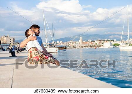 Stock Photo - Young couple sitting on harbour, Split, Dalmatia, Croatia. Fotosearch