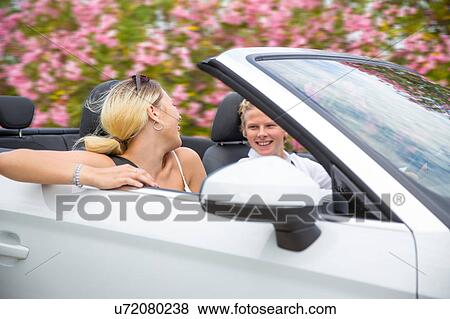 Stock Photo - Young couple speeding in convertible past blossoms, Majorca, Spain. Fotosearch