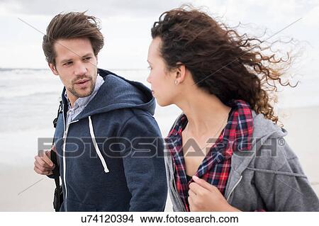 Picture - Young couple strolling on windswept beach, Western Cape, South Africa. Fotosearch