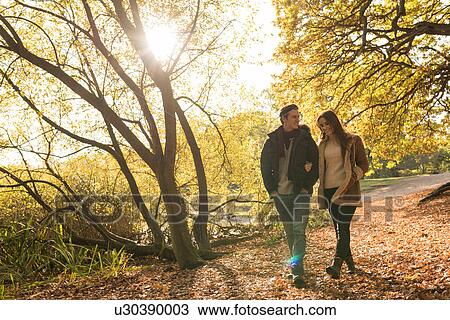 Young couple walking in forest, arm in arm, smiling View Large Photo Image Stock Image - Young couple walking in forest, arm in arm, smiling. Fotosearch