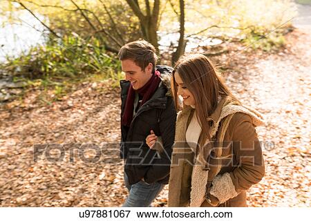 Stock Photo - Young couple walking in park, arm in arm, smiling. Fotosearch
