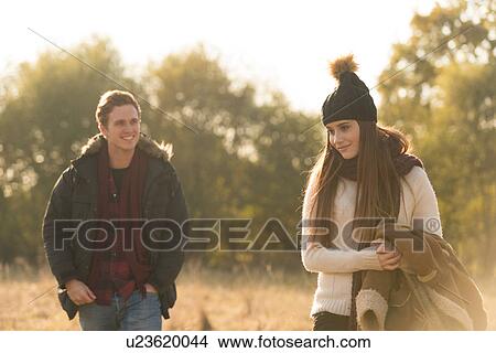 Young couple walking through field, smiling View Large Photo Image Picture - Young couple walking through field, smiling. Fotosearch