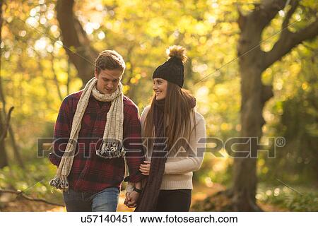 Young couple walking through forest, holding hands, smiling View Large Photo Image Stock Image - Young couple walking through forest, holding hands, smiling. Fotosearch