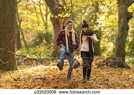Young couple walking through forest, holding hands, smiling View Large Photo Image Stock Photo - Young couple walking through forest, holding hands, smiling. Fotosearch