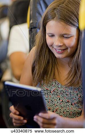 Stock Photography - Young girl using digital tablet in airplane. Fotosearch