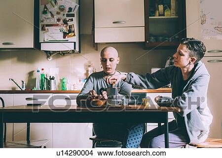 Picture - Young lesbian couple pouring espresso in kitchen. Fotosearch