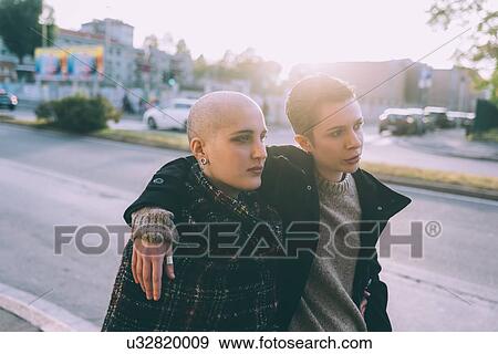 Stock Photo - Young lesbian couple strolling along city street. Fotosearch