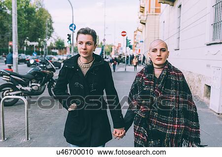 Young lesbian couple walking along city street holding hands View Large Photo Image Stock Image - Young lesbian couple walking along city street holding hands. Fotosearch
