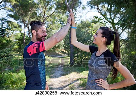 Stock Photo - Young male and female runners high fiving each other in park, Split, Dalmatia, Croatia. Fotosearch