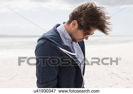 Young man alone on windswept beach looking down, Western Cape, South Africa View Large Photo Image Stock Photo - Young man alone on windswept beach looking down, Western Cape, South Africa. Fotosearch