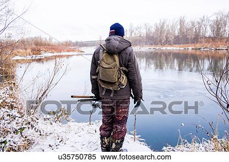 Young man standing beside lake, rear view View Large Photo Image Stock Photography - Young man standing beside lake, rear view. Fotosearch