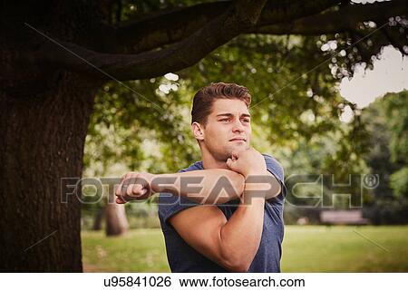 Stock Photograph - Young man training, warming up in park. Fotosearch