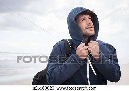 Stock Image - Young man wearing hoody on beach, Western Cape, South Africa. Fotosearch