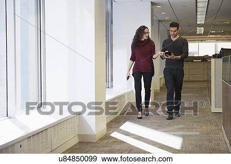 Young people walking side by side in corridor with digital tablet View Large Photo Image Stock Photo - Young people walking side by side in corridor with digital tablet. Fotosearch