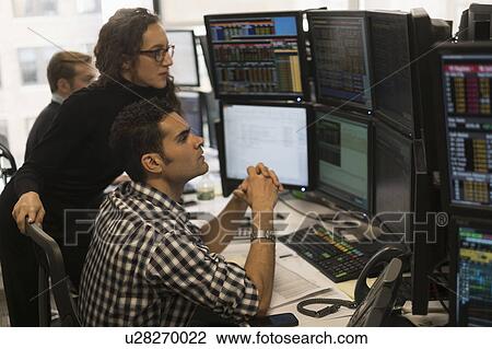 Stock Image - Young traders analyzing computer data. Fotosearch