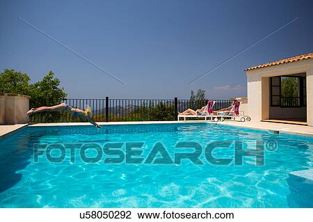 Stock Image - Young woman diving into boutique hotel swimming pool, Majorca, Spain. Fotosearch