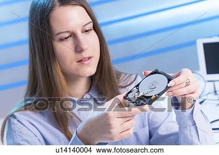 Young woman examining computer hard drive View Large Photo Image Picture - Young woman examining computer hard drive. Fotosearch
