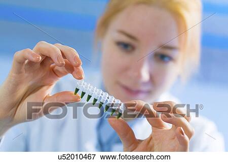 Stock Photo - Young woman holding pcr tubes. Fotosearch