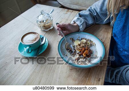 Young woman in cafe, eating muesli, mid section View Large Photo Image Stock Photo - Young woman in cafe, eating muesli, mid section. Fotosearch