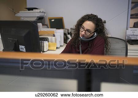 Young woman in cubicle talking via telephone View Large Photo Image Stock Image - Young woman in cubicle talking via telephone. Fotosearch