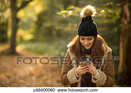 Young woman in forest, looking at smartphone, smiling View Large Photo Image Stock Image - Young woman in forest, looking at smartphone, smiling. Fotosearch