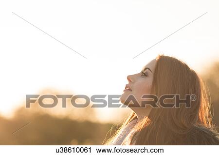 Stock Image - Young woman in rural setting, carefree expression. Fotosearch