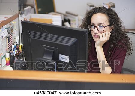 Young woman looking at computer monitor View Large Photo Image Stock Photo - Young woman looking at computer monitor. Fotosearch