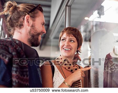 Stock Photo - Young woman pointing at sweater in shop window to boyfriend. Fotosearch
